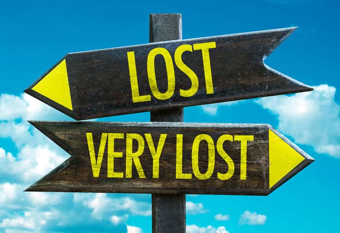 Directional signpost with "LOST" and "VERY LOST" arrows against blue sky