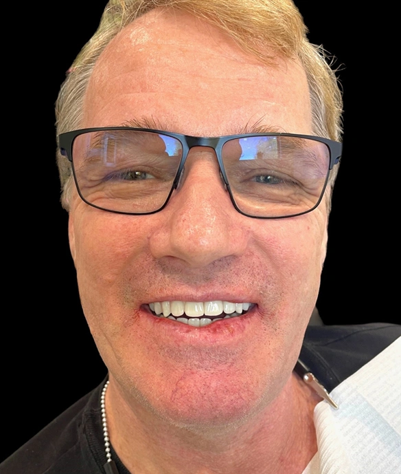 Man wearing glasses smiling at camera, dental office portrait headshot